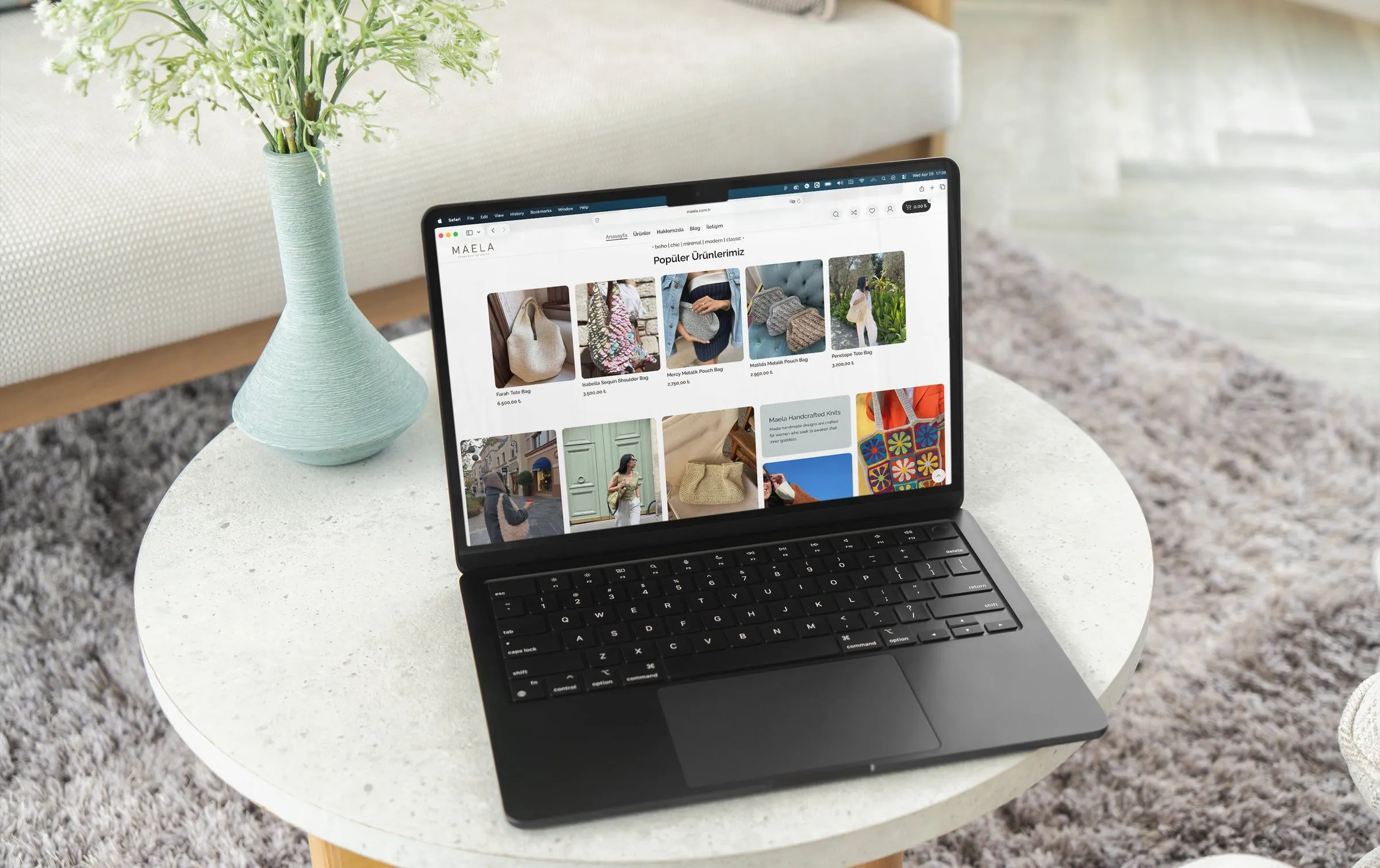 The MAELA online store open on a laptop on a round side table, showing its popular handmade bags