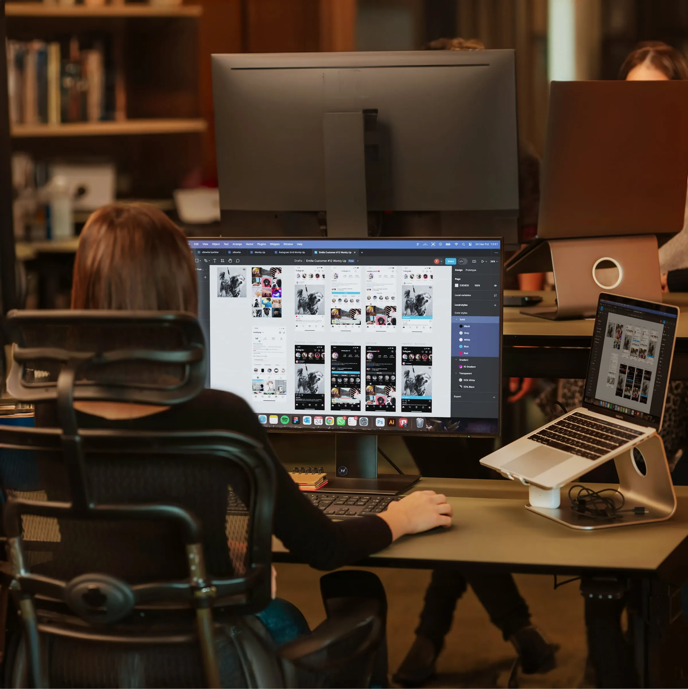 Someone working on a website design at a desk with two screens