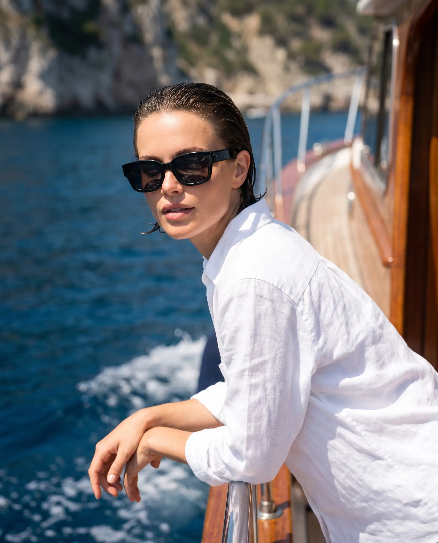 Eine Frau mit Sonnenbrille, die sich an die Reling eines Bootes lehnt